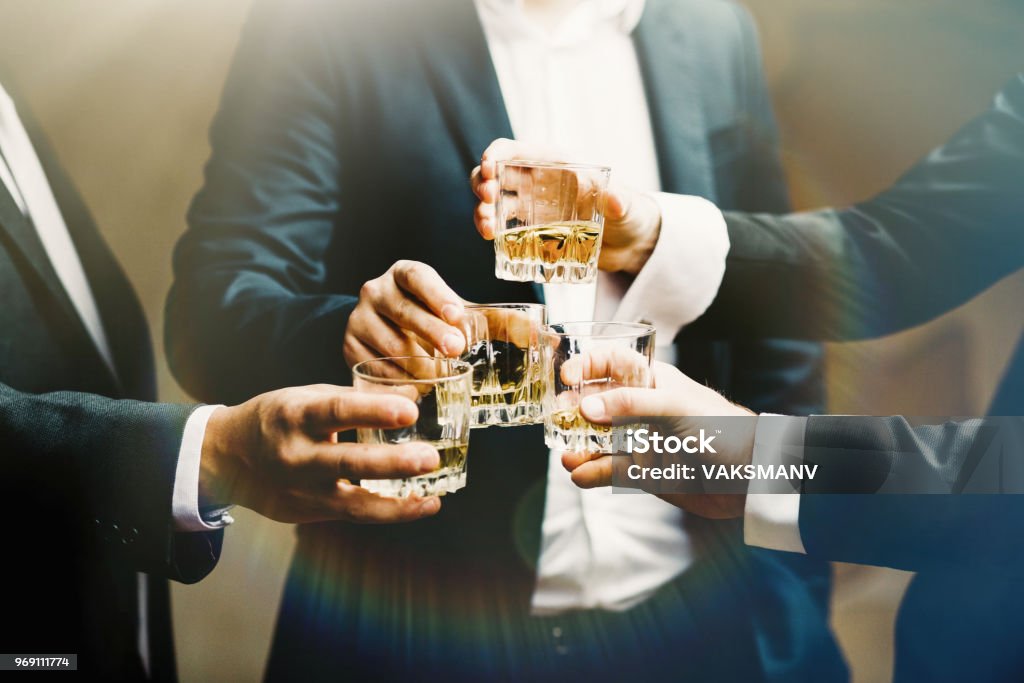 Hands of mans with glasses of whiskey, celebrating and toasting Group of friends guys with glasses of whiskey Whiskey Stock Photo