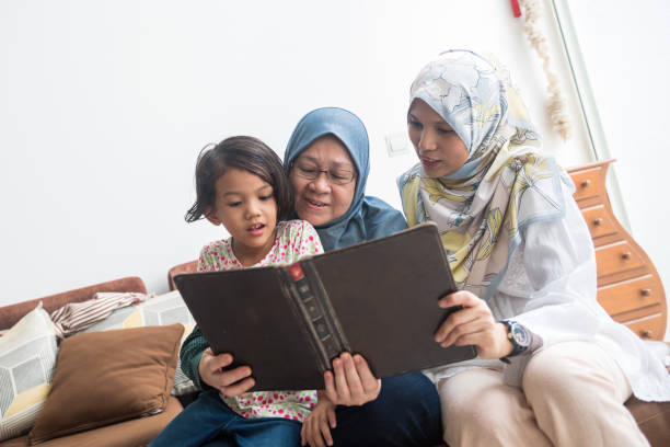 trois générations de femmes lisant un livre - grandparent senior adult child reading photos et images de collection