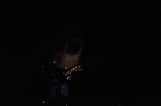 Welder welding metal in workshop with sparks