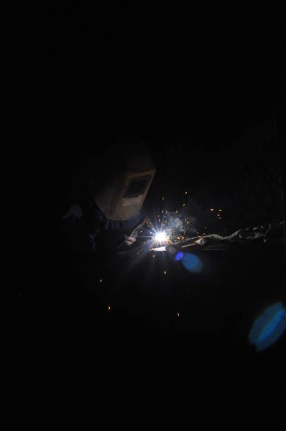 Welder welding metal in workshop with sparks