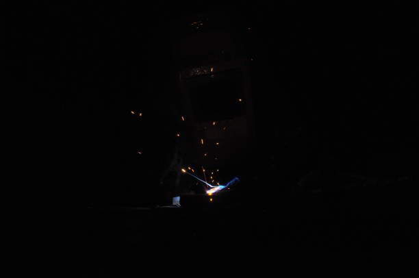 Welder welding metal in workshop with sparks