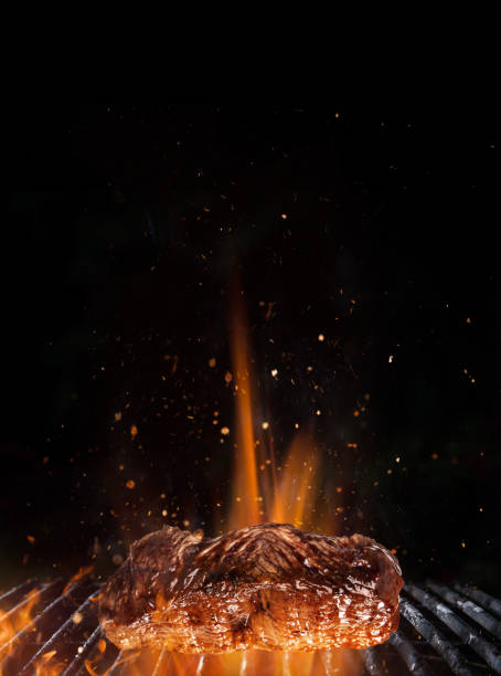 istock Tasty beef steak on cast iron grate with fire flames 969118440