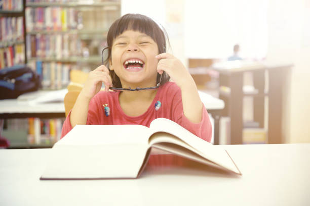 istock Adorable little girl reading book in library. 969119236