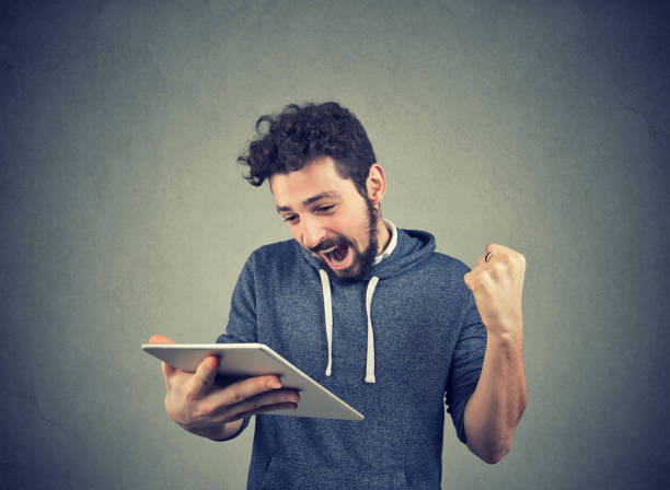 istock Happy man with tablet holding fist up 969122440