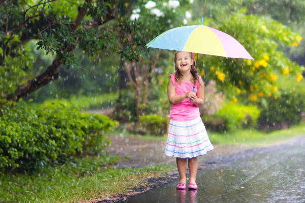 istock Kid with umbrella playing in summer rain. 969123910