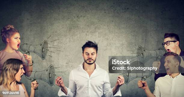 Meditating Businessman Paying No Attention To Crowd Of Screaming Angry People Stock Photo - Download Image Now