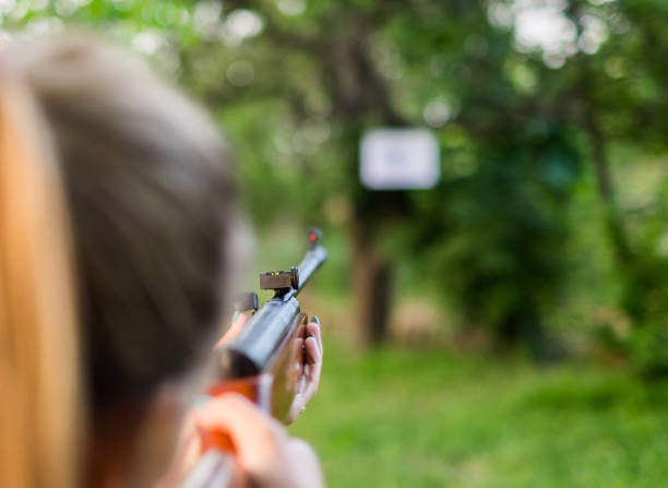 Group of young teenage girls aiming with a rifle on target on shooting training.
