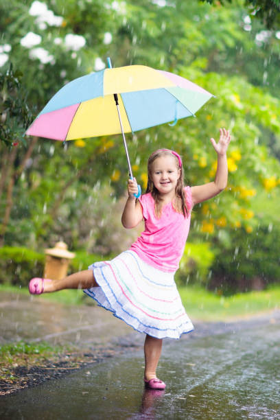 istock Kid with umbrella playing in summer rain. 969136616