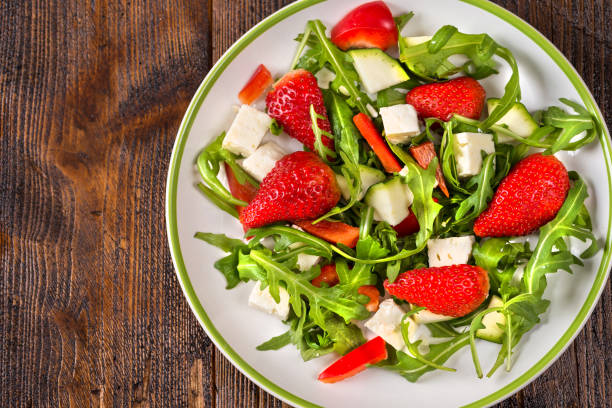 istock Fresh vegetable strawberry salad on white plate on natural rustic desk. 969155382