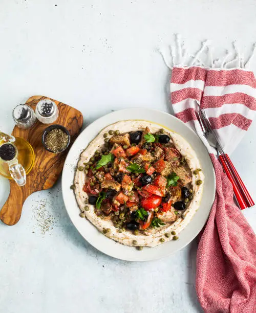 fresh Greek dakos salad on a layer of hummus. light vegan summer nutritious recipe