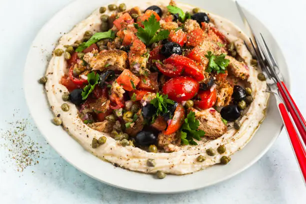 fresh Greek dakos salad on a layer of hummus. light vegan summer nutritious recipe