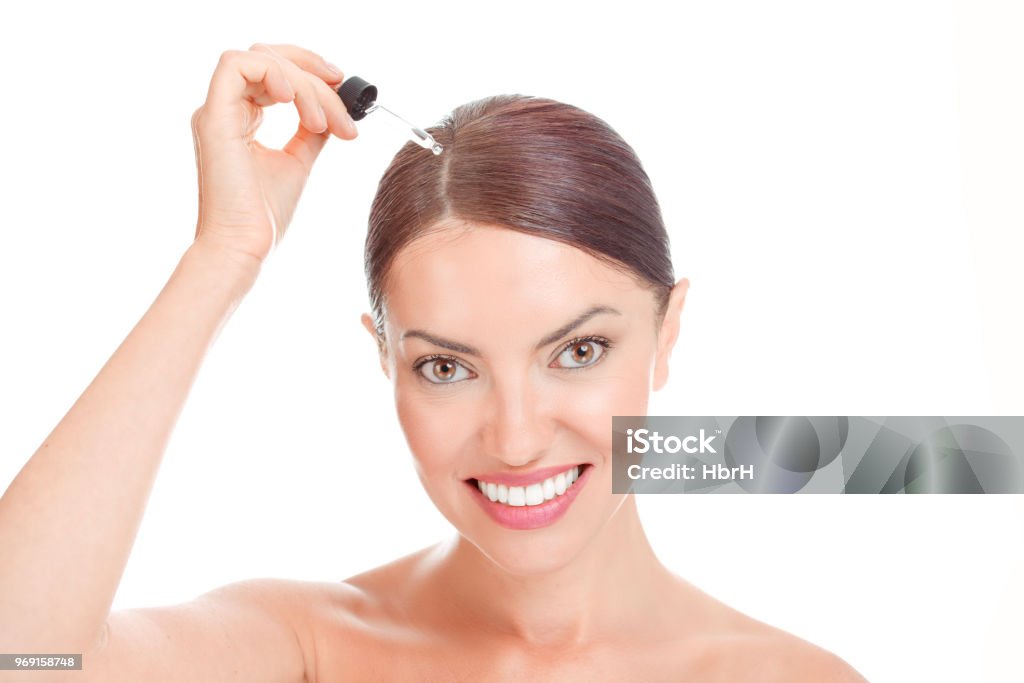 Woman aplying serum essence, essential oils to her hairline Hair Serum For woman. Woman applying serum essence essential oils to her hairline for growth against gray hair solution smiling happy isolated on white. Positive face expression mixed race latina girl Hair Stock Photo