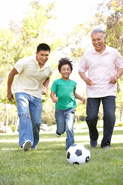 grand-père avec son fils et son petit-fils jouer au football - grandfather grandson active seniors senior adult photos et images de collection