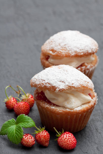 istock Cupcakes  stuffed with white cream and wild strawberry on black stone background 969170424