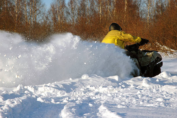 all terrain vehicle in motion at winter stock photo