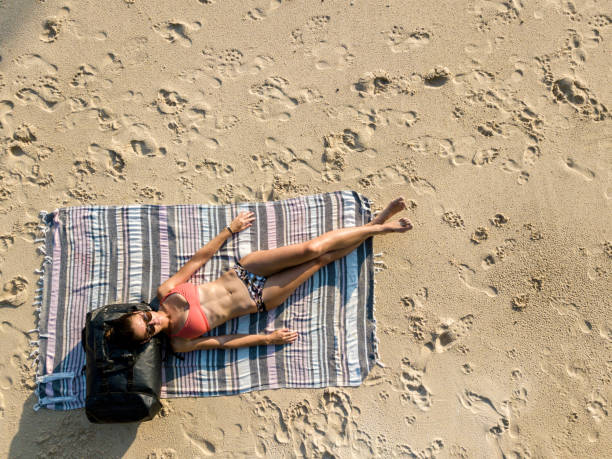 istock Young woman sunbathing on sandy beach with backpack under her head 969185120