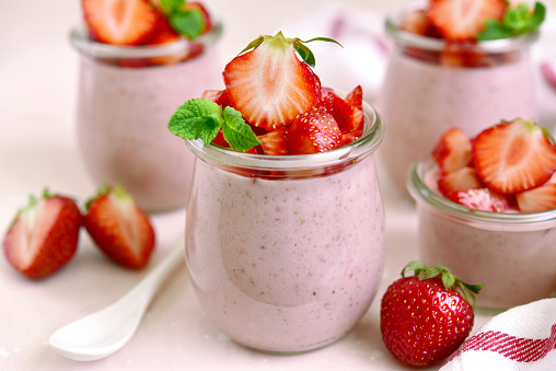 Homemade strawberry mousse in a vintage glass jar on a light slate, stone or concrete background.