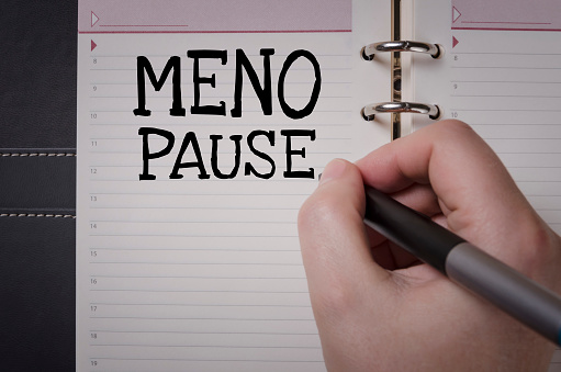 Woman hand writing Menopause word. Health care and medical concept.