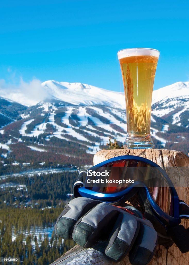 Luego de esquiar refrigerios. Cerveza y engranajes con las montañas. - Foto de stock de Cerveza libre de derechos