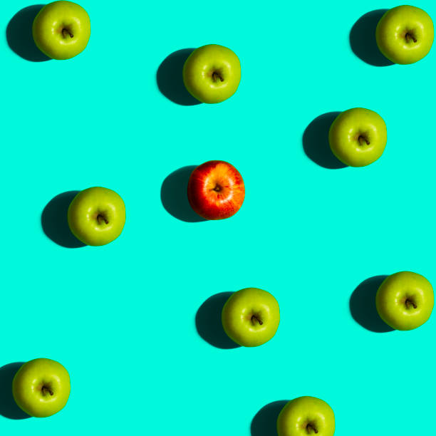 istock Green and Single Red Apple on a Blue Background 969220124
