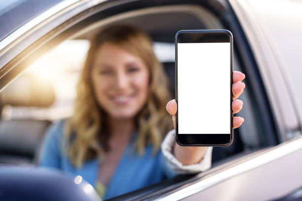 istock Young woman in auto shows smartphone with blank screen 969220338