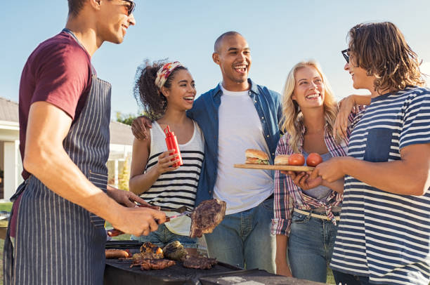 amici che si godono il barbecue per il pranzo - cotto alla griglia foto e immagini stock