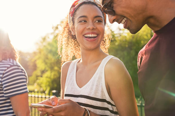 pareja joven mediante teléfono móvil - couple young women cheerful outdoors fotografías e imágenes de stock