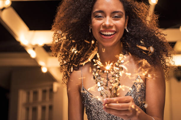 Smiling woman with bengal light Portrait of young african girl holding sparkle stick under the patio outdoor. Happy smiling woman celebrating with fireworks. Elegant woman holding a bengal light for new year"u2019s eve party. new years 2019 stock pictures, royalty-free photos & images