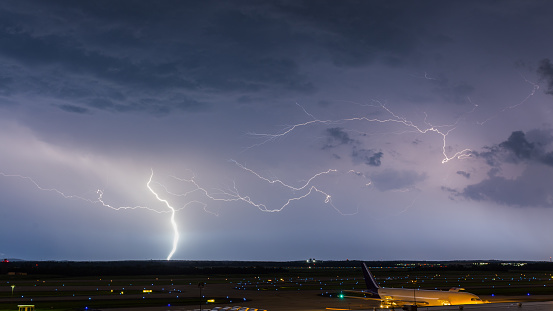 A bolt of lightning and multiple streamers streak across the night sky over Dulles International Airport as a FedEx Boeing 767 takes on another cargo load