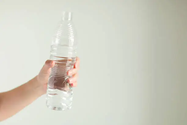 A hand is holding of drinking water bottle on white background.