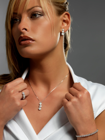 A vertical closeup of a pearl necklace around a Caucasian female's neck.