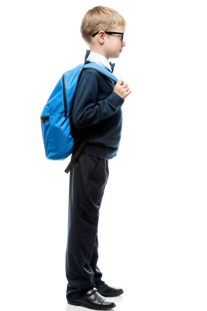 istock boy in school uniform with backpack in full length side view, portrait isolated 969259058