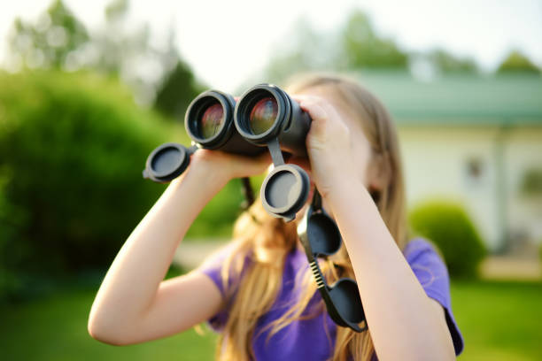 istock Funny little girl looking through binoculars on sunny summer day 969264710