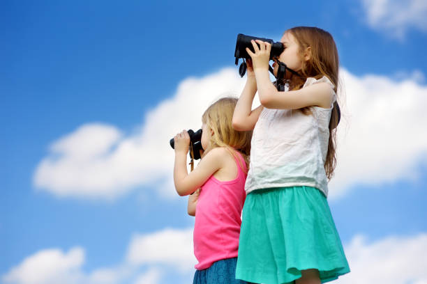 istock Two cute little girls looking through binoculars on sunny summer day 969264764