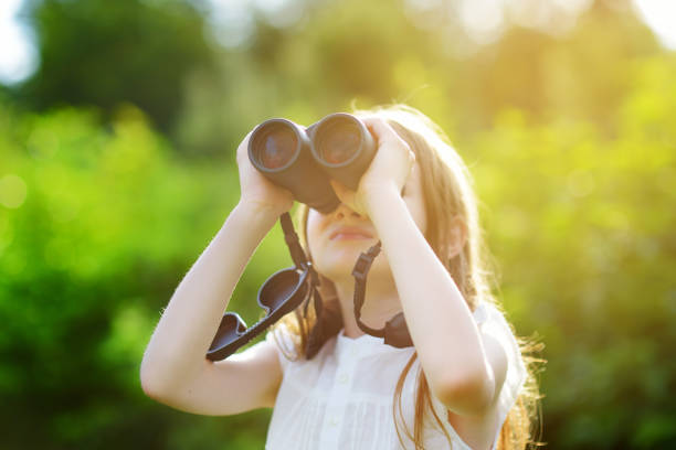 istock Funny little girl looking through binoculars on summer day 969264802