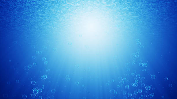 istock Blue ocean waves from underwater with bubbles. Light beam rays shining through. 969264960