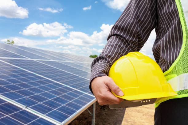istock Young business man engineer hold yellow helmet at solar panel power plant construction site background 969274286