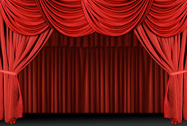 A theater stage draped with red curtains stock photo