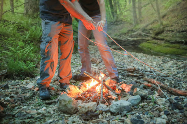 istock Two People Tending Building Camping Campfire Near Stream at Twilight 969305076