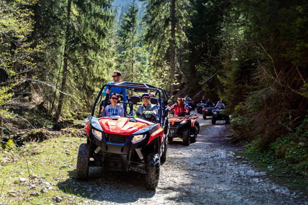 un groupe de touristes se déplace sur les vtt et utv sur les montagnes - off road vehicle quadbike mud dirt road photos et images de collection