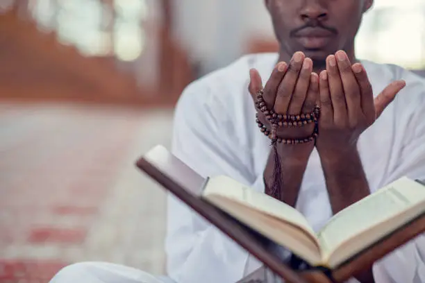 Photo of African Muslim Man Making Traditional Prayer To God While Wearing Dishdasha