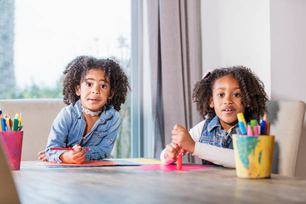 istock Mixed race sisters doing arts and crafts, pens, paper 969315228