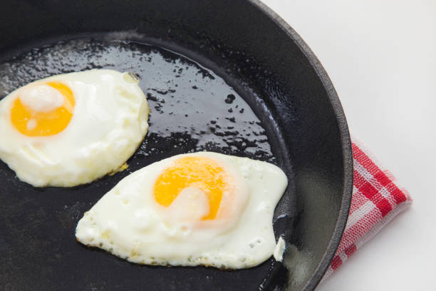huevos fritos en una sartén de hierro fundido - sunnyside fotografías e imágenes de stock