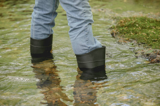istock Jeans and Rubber Boots Legs Standing in Nature Stream Water 969330428