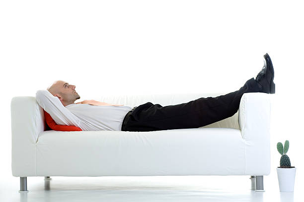 Adult male lying down on white couch stock photo