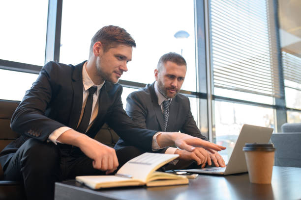istock Confident business colleagues discussing report while using laptop and elaborating strategy in business hall 969342890