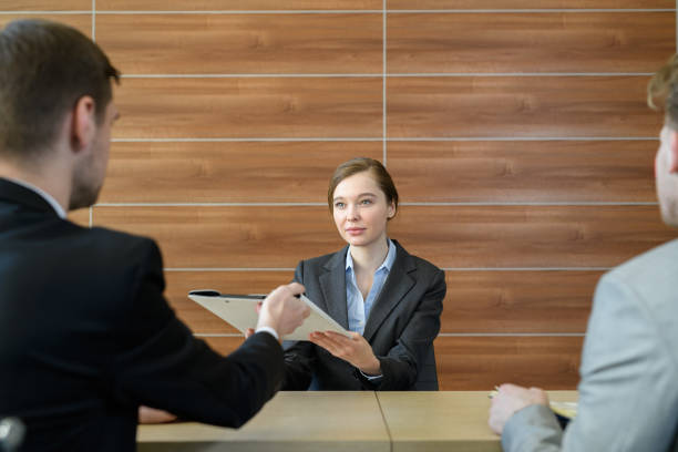 istock Serious confident female job applicant giving folder with her portfolio while talking to recruiters in meeting room 969342932