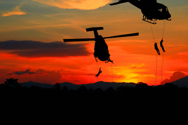 istock Silhouette Soldiers rappel down to attack from helicopter with warrior beware danger On the ground sunset Background blur and copy space add text ( Concept stop hostilities To peace) 969348332