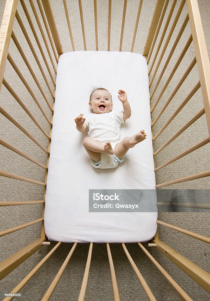 Aerial view of a happy baby girl in a wooden crib A small baby girl lying in a crib Affectionate Stock Photo