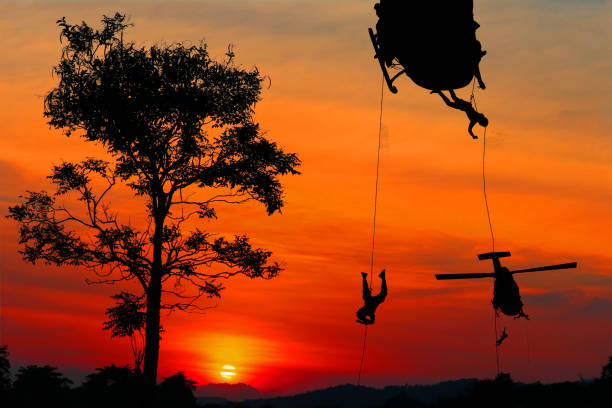 istock Silhouette Soldiers rappel down to attack from helicopter with sunset and copy space add text ( Concept stop hostilities To peace) 969352962